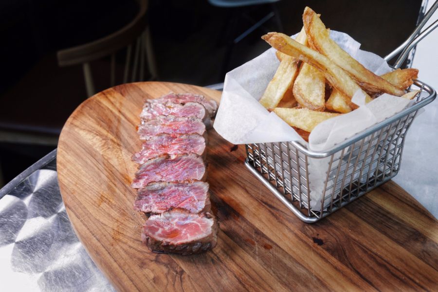 Une pièce de bœuf tranchée et des frites dans leur panier