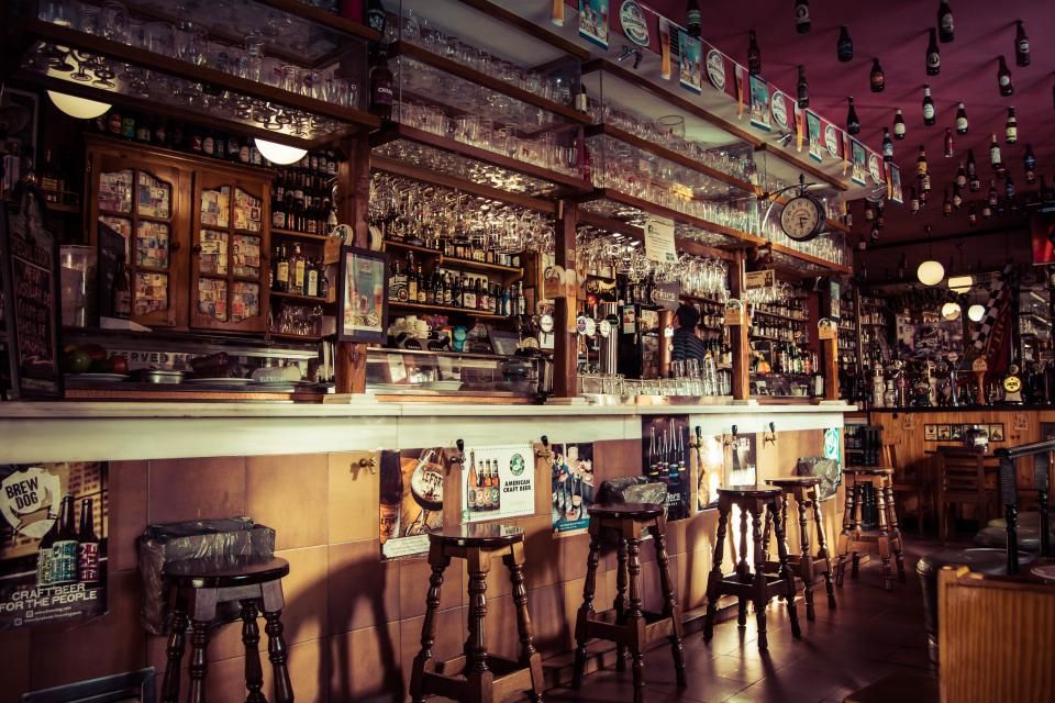 Une salle de brasserie aux boiseries sombres, le comptoir et ses tabourets